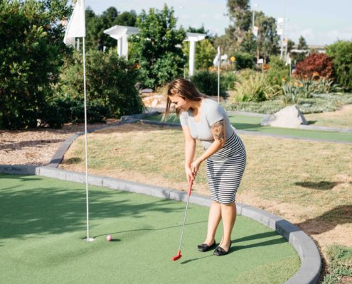 Young people playing mini golf